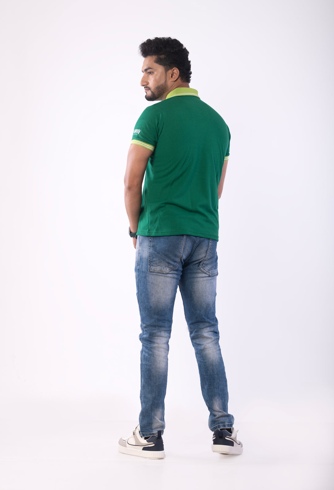 Man wearing a green polo shirt and blue jeans on a white background