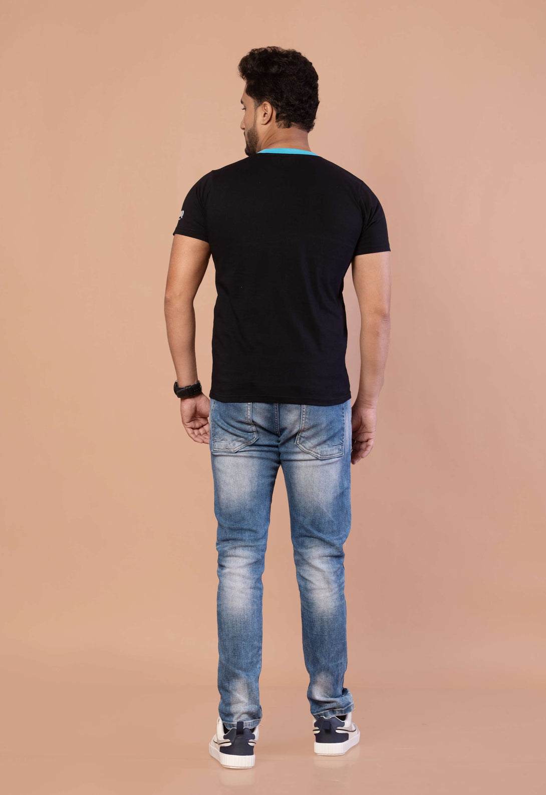 Man wearing a black t-shirt and blue jeans on a beige background
