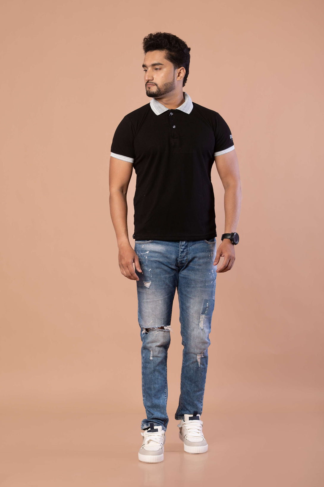 Man wearing a black polo shirt and blue jeans on a beige background