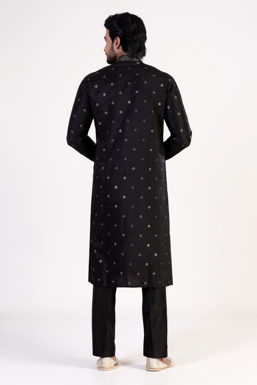 Man wearing a black embroidered sherwani on a white background
